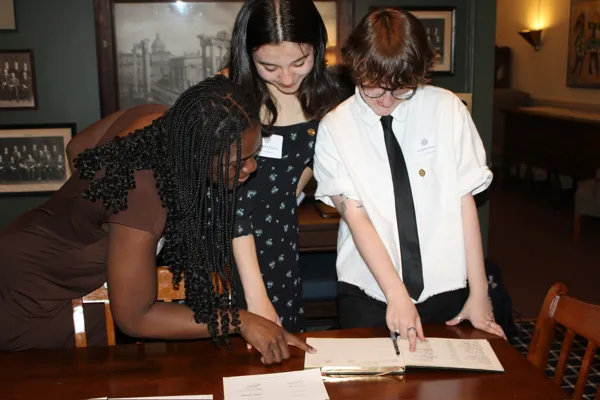 New Delegates sign the guestbook in the Aurelian Reading Room at the Graduate Club.